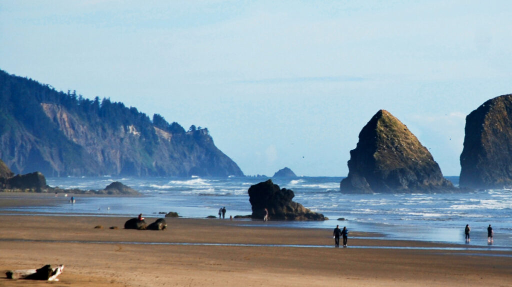 View of the people wandering around the Cannon Beach with the rock formations in the background
