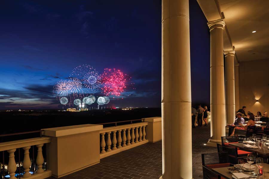 People admiring the fireworks while enjoying their food at the Capa terrace