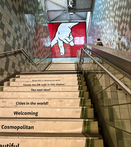 Words and phrases on the steps of Capitol Hill light rail station with an art piece on the landing above