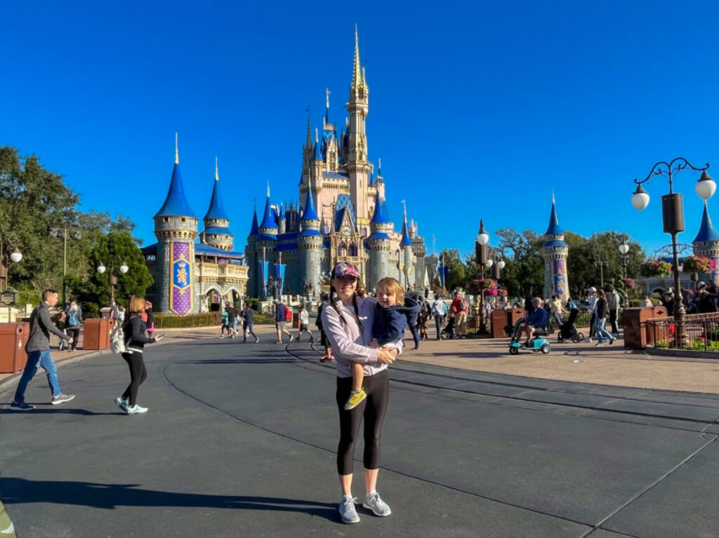 Author Katie Neufeld and son posing in front of Cinderella Castle