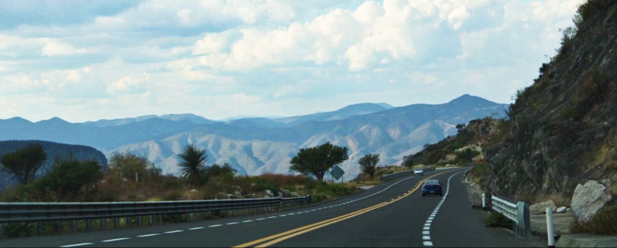 View of cars passing in the local highway surrounded with beautiful mountains.