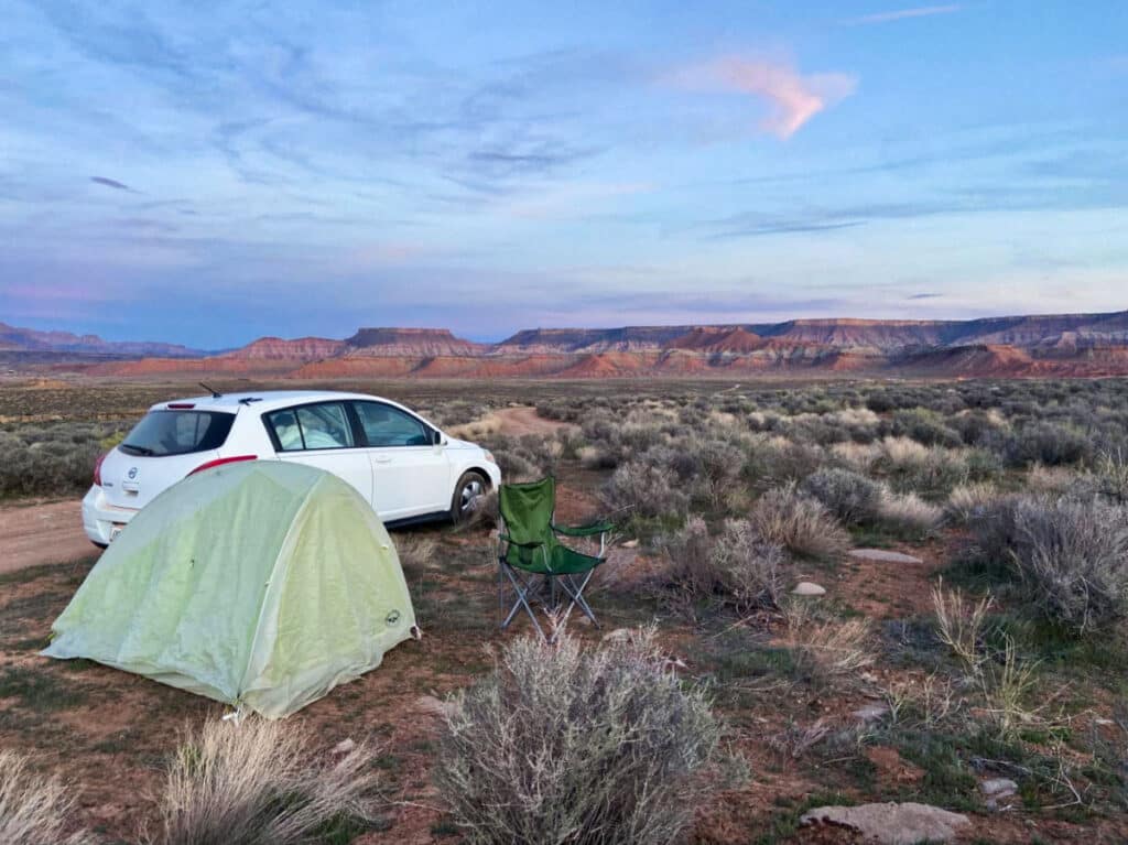 A camping tent and chair near the car on the campground in Utah at dusk