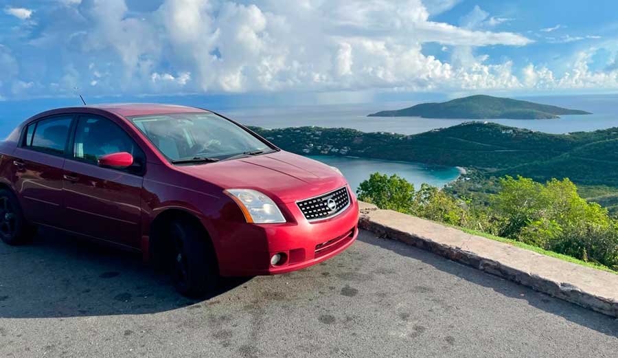 A red car with an overlooking view of USVI on its background