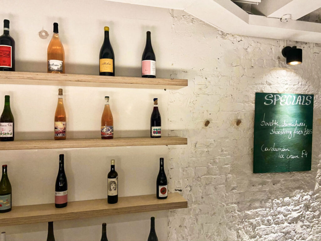 View of the variety of liquor on the wooden shelves against the white brick wall inside the Carousel