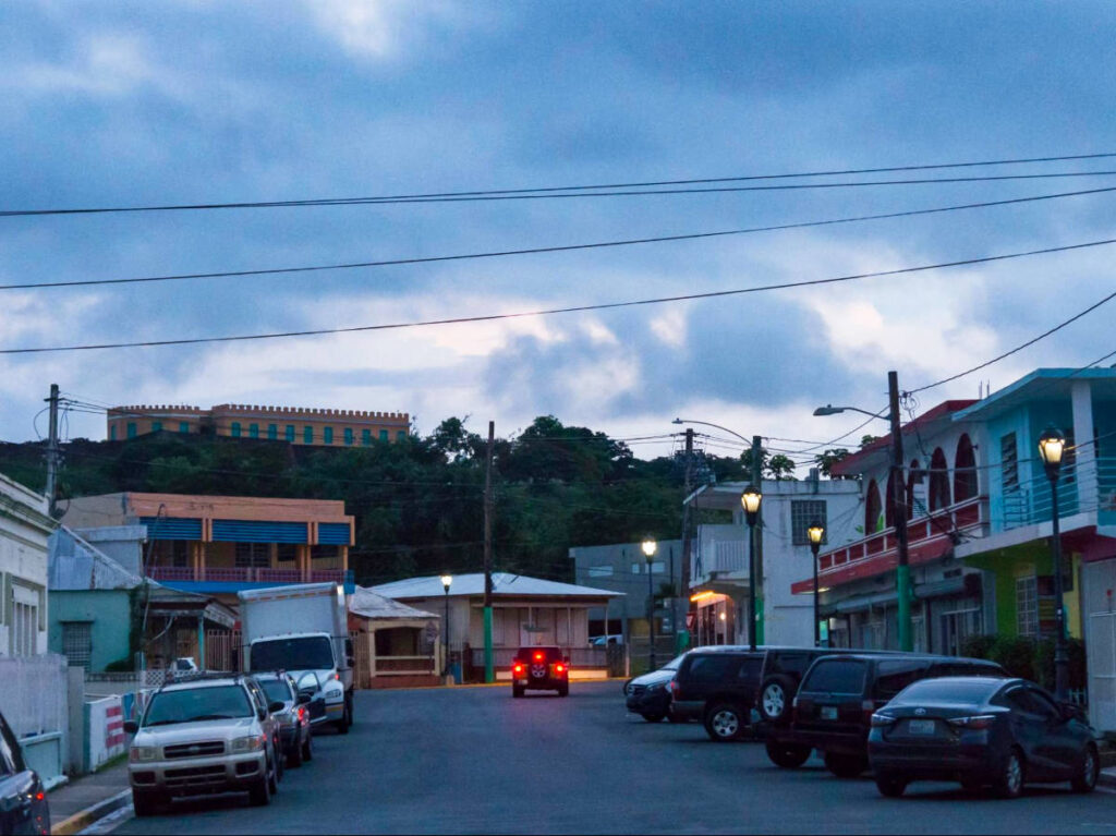 View of the parked cars and a car signaling in the street of Puerto Rico at night time