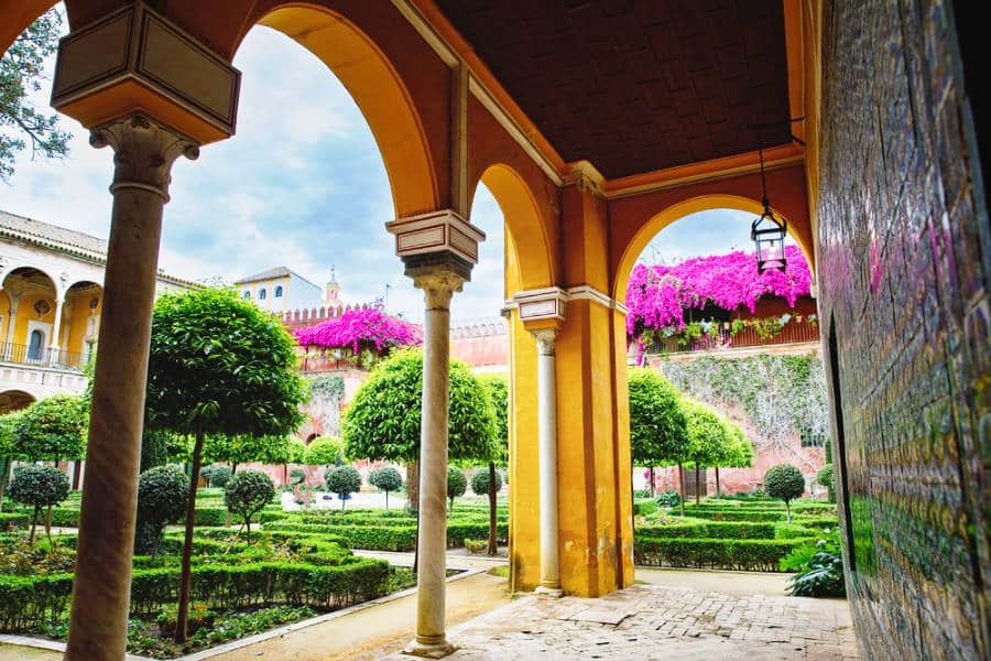 View of the bright yellow and unique style of the arches in Casa de Pilatos in Seville with the beautiful landscape in the background