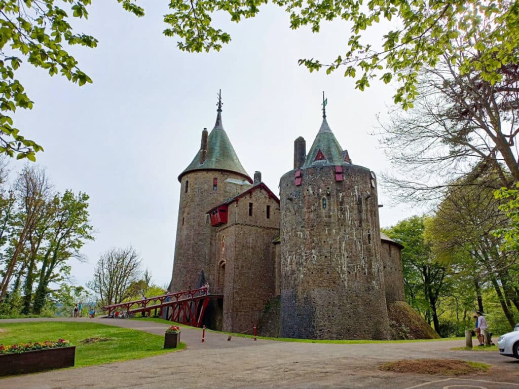 Exterior view of the Castell Coch with red windows and bridge leading to the entrance