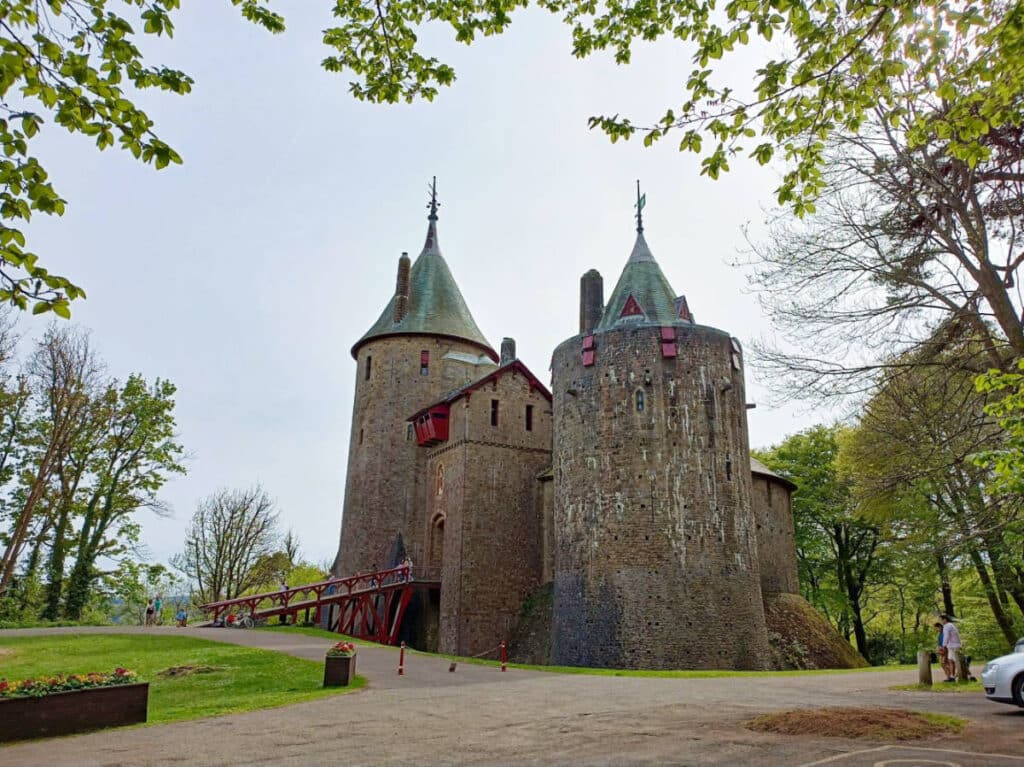 Exterior view of the Castell Coch with red windows and bridge leading to the entrance