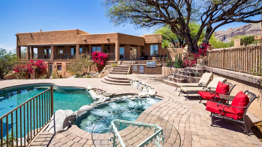 Outdoor view of a luxury house with swimming pool and hot tub in a desert environment