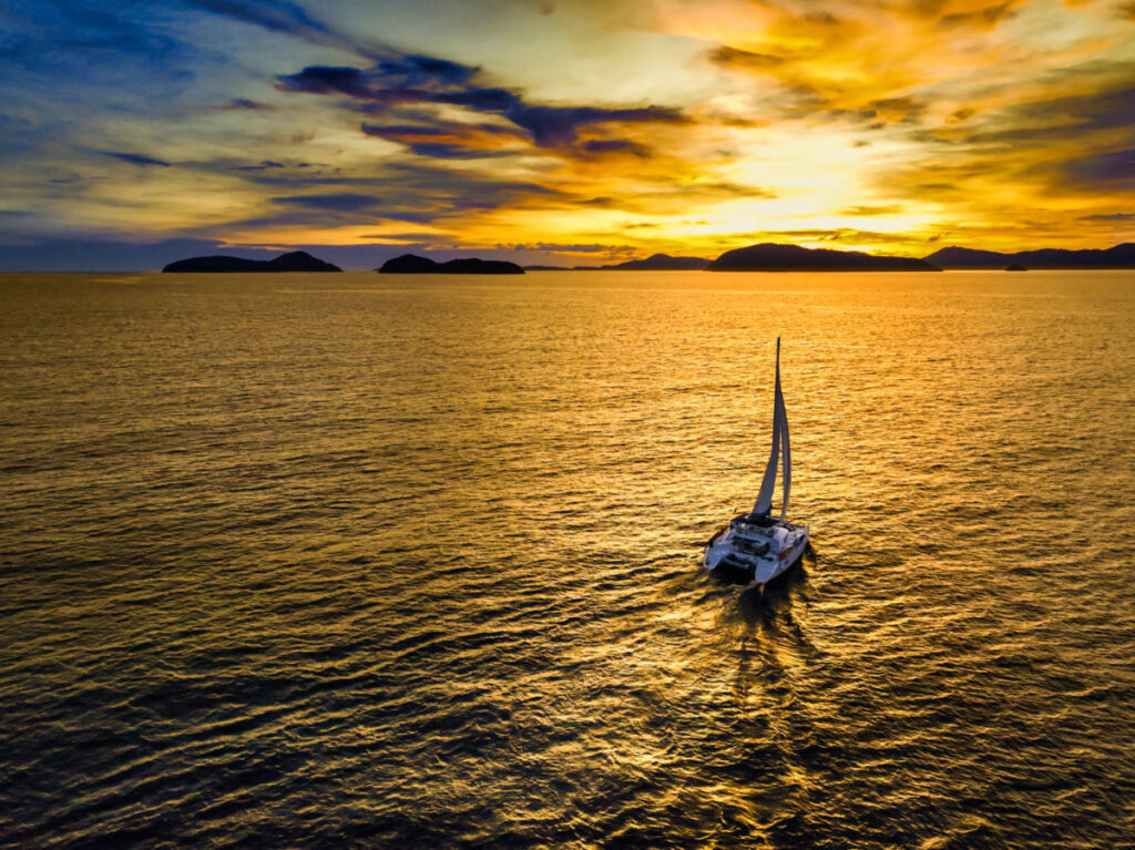 A catamaran sailing at sunset