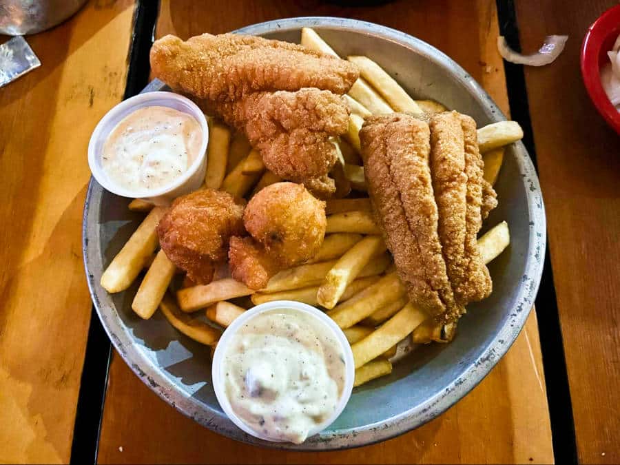 A plate of fries topped with fried catfish and dipping sauces from Cock of the Walk