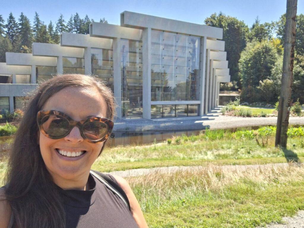 The author Catherine Driver, smiling for a photo outside the building of Museum of Anthropology