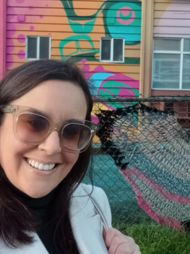 The author Catherine posing for a photo with the colorful mural at Mount Pleasant     