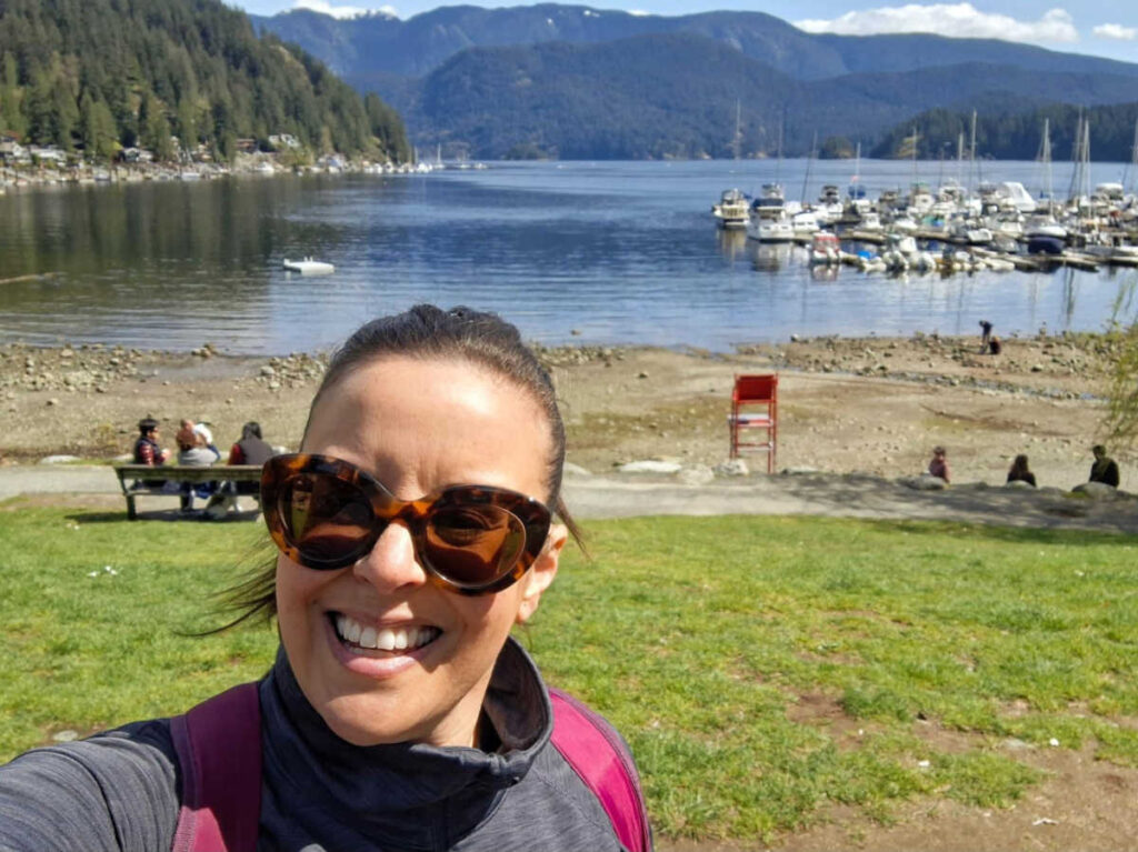 The author Catherine Driver smiling for a photo with the marina on the Deep Cove in the background