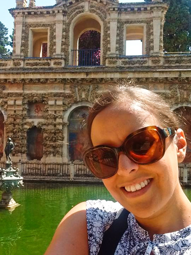The author Catherine Driver, smiling for a photo in front of the Royal Alcázar