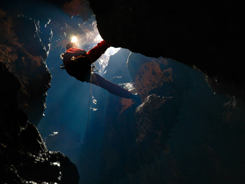 A man caver abseiling seen from under the water