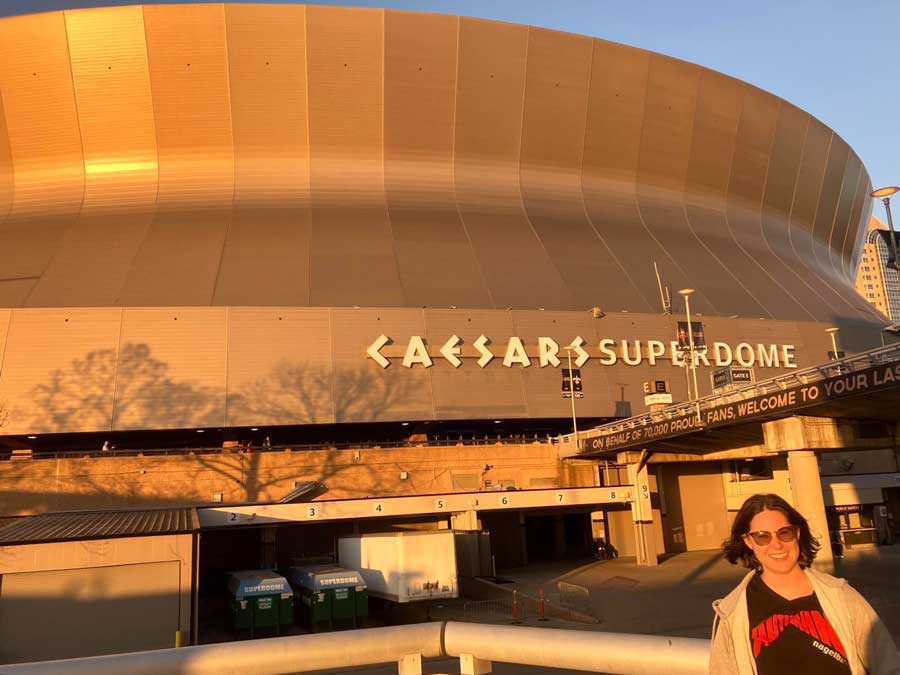 The author smiling for a photo with the Ceasars Superdome on her background