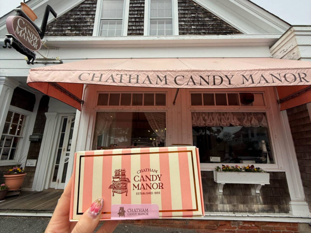 Holding a box of candy outside Chatham Candy Manor