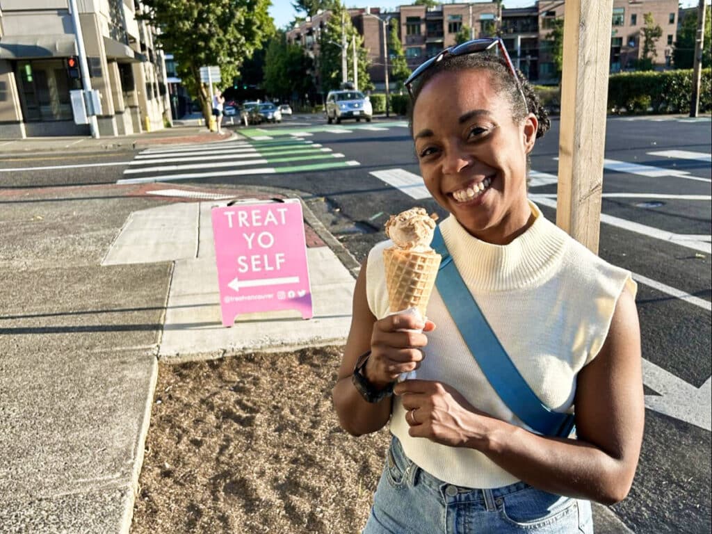 The author Chelsea Booker, smiling for a photo while holding a cone of ice cream from Treat