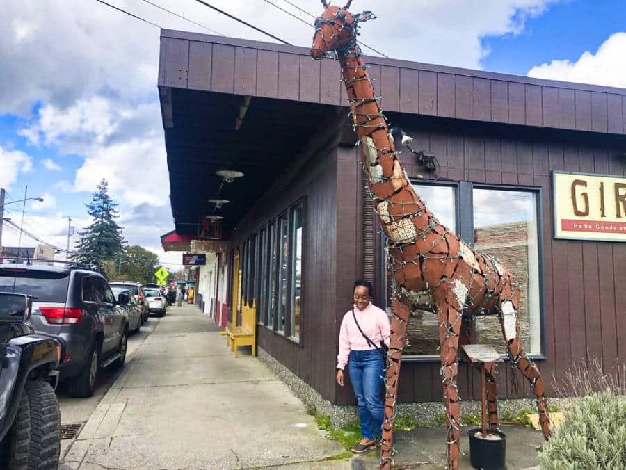 The author Chelsea Booker posing beside the giraffe sculpture in downtown Vashon