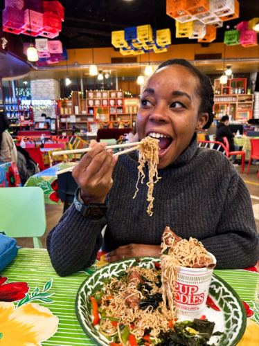 The author Chelsea Booker, eating Mee Goreng Kee Mow noodle dish at Asean Streat Food Hall