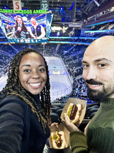 The author Chelsea Booker and her husband, posing for a photo with their food inside the Climate Pledge Arena