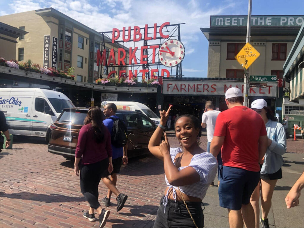 The author, Chelsea Booker pointing at the Pike Place Market signage