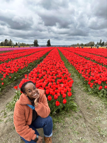 The author Chelsea Booker, posing for a photo with the vibrant and blooming tulip fields in the background