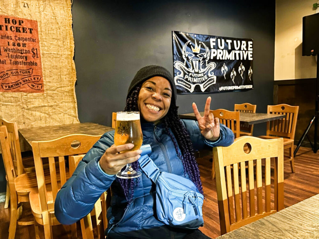 The author Chelsea Booker, posing for a photo while holding a glass of beer