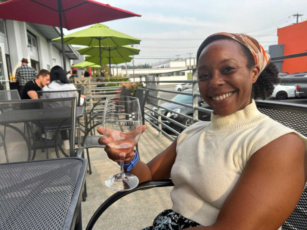 The author Chelsea Booker, smiling for a photo while sampling a rosé at Patterson Cellars Tasting Room
