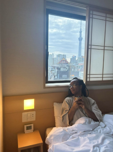 The author Chelsea Booker sipping her coffee on the bed while overlooking the view from the window