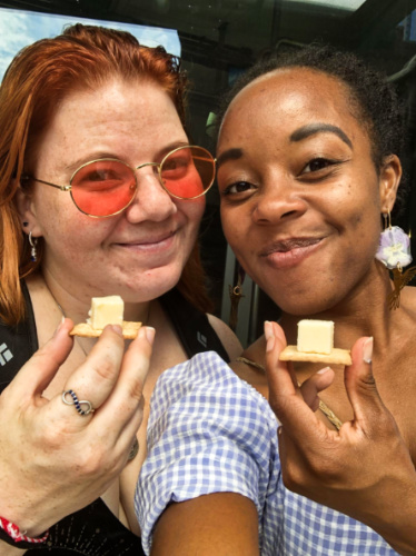 The author Chelsea Booker and her friend, posing for a photo with a cube of Beecher’s cheese on a cracker