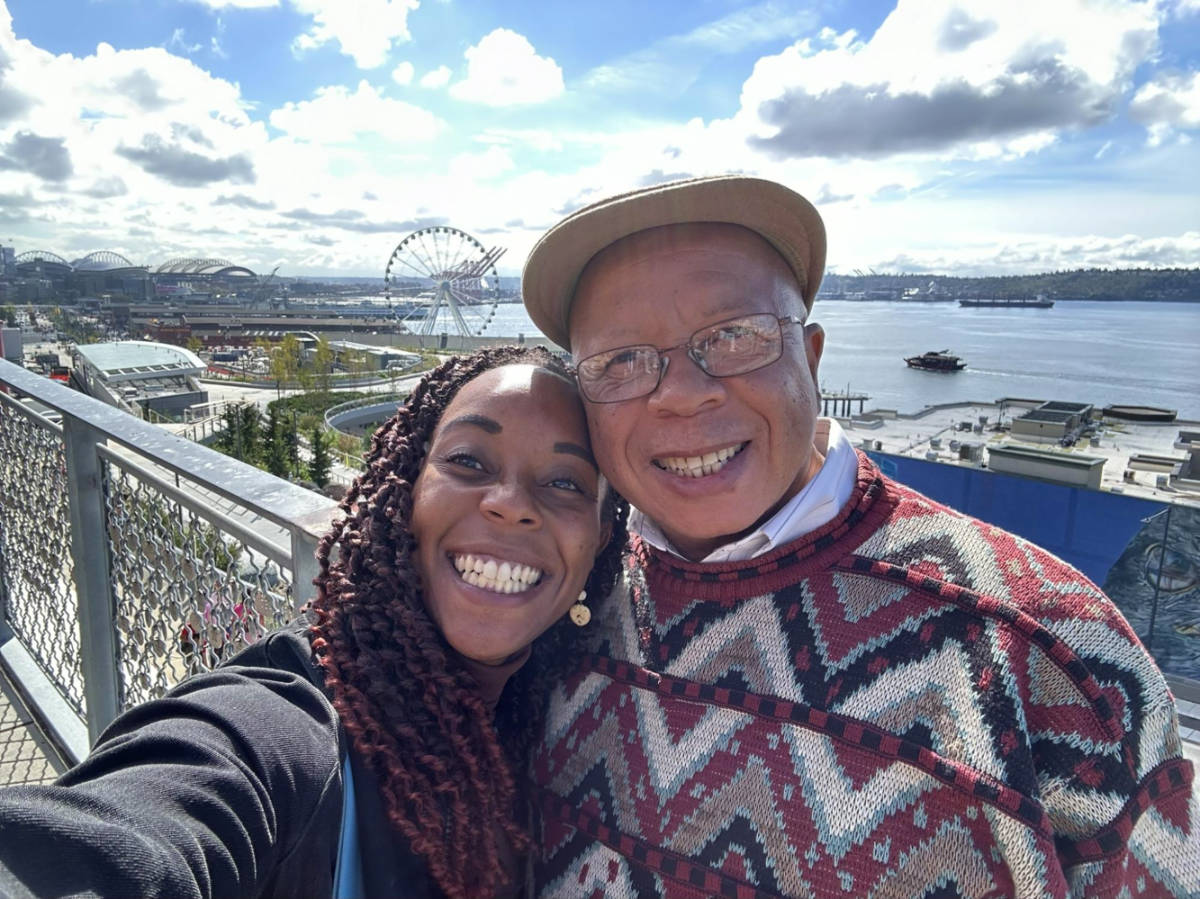 Author Chelsea and her dad taking a selfie in Pike Place Market with the waterfront in the background