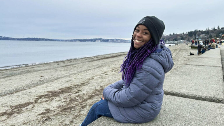 The author Chelsea sitting in front of the beach in winter