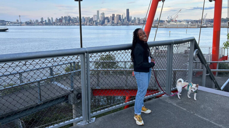 The author Chelsea Booker, posing for a photo with her dog at Jack Block Park in West Seattle with skyline views in the background