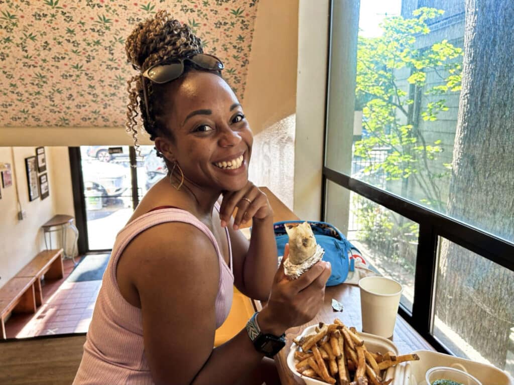 The author Chelsea Booker, smiling for a photo with her food from Spice Waala