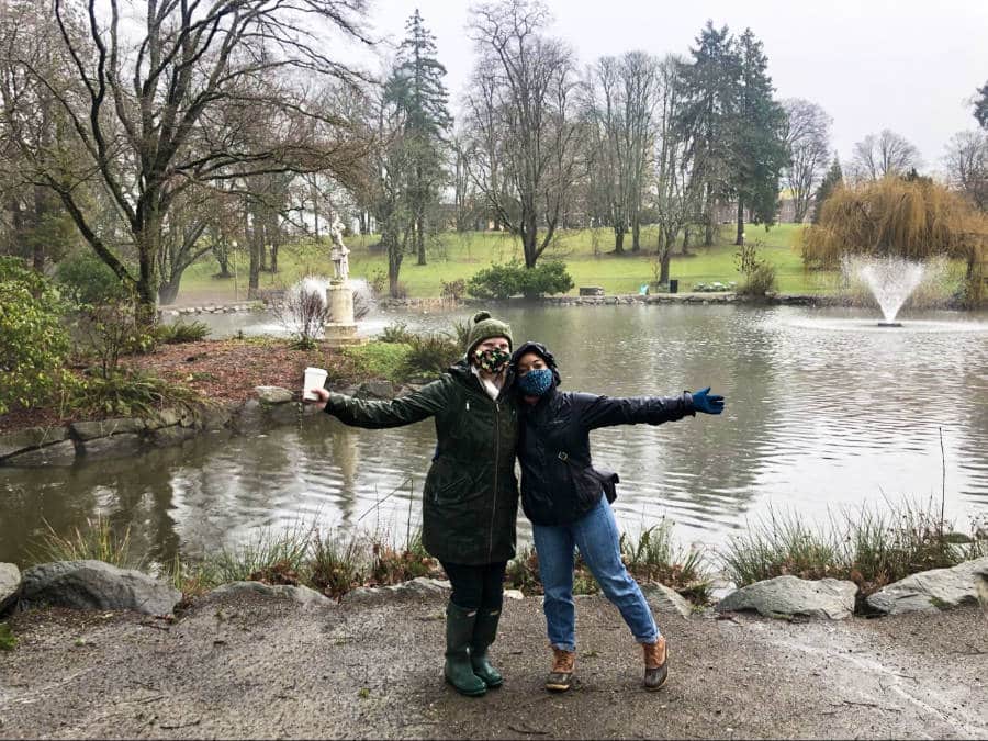 The author Chelsea Booker and her friend posing near the fountain and lake at Wright Park in Hilltop on a rainy day