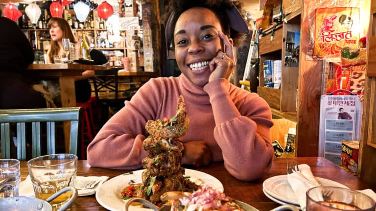 The author Chelsea Booker smiling with the Chengdu spicy chicken wings in Nue