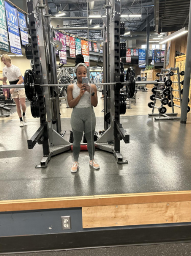 The author Chelsea Booker, taking a mirror selfie on a gym