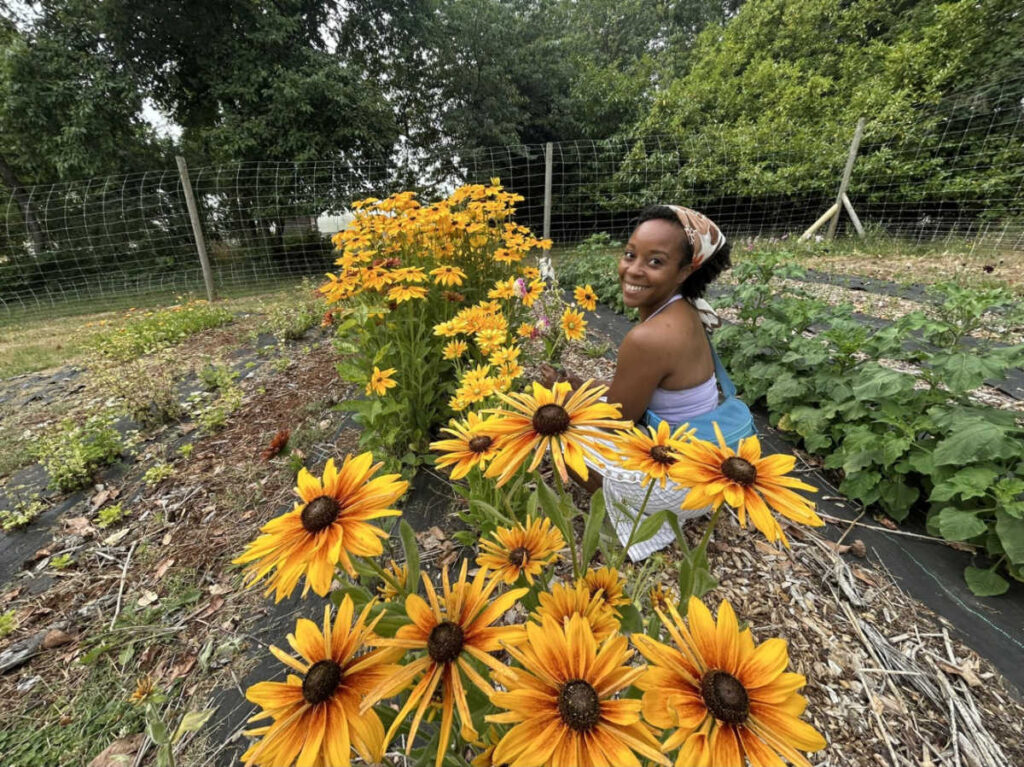 The author Chelsea Booker, smiling for a photo at a field with blooming flowers