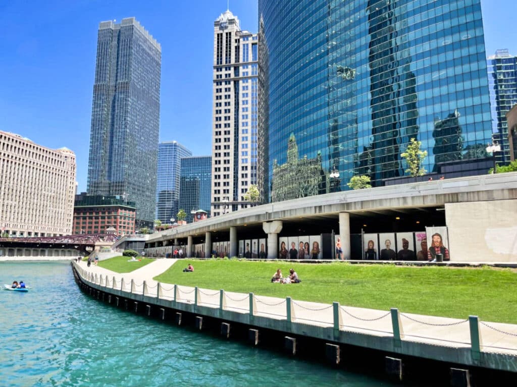View of the people relaxing at the lawn in the Chicago Riverwalk with the skyline in the background