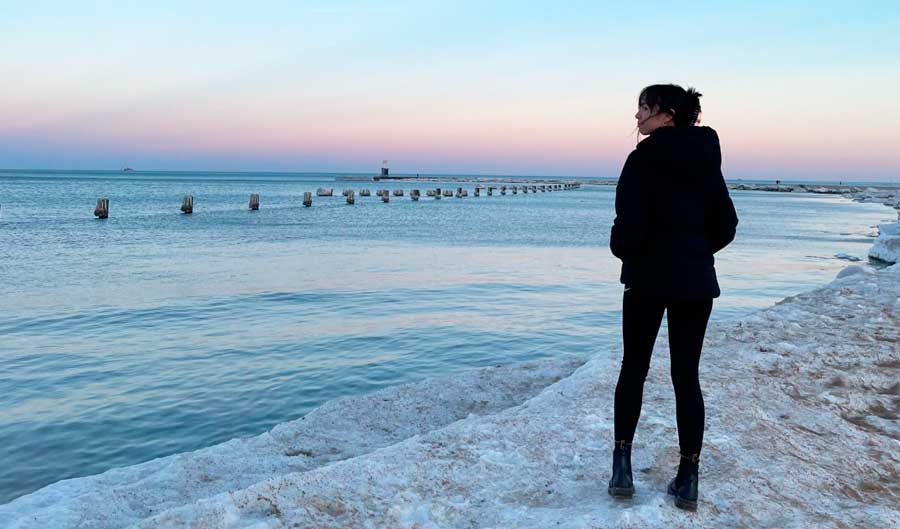 The author posing for a photo with a colorful sky on her background