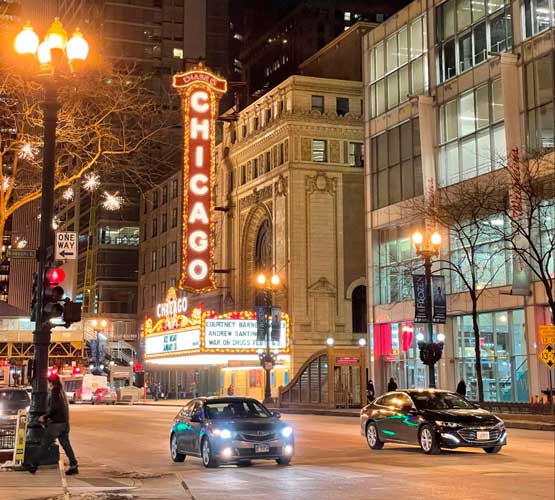 Cars passing along the Chicago Theatre District at night
