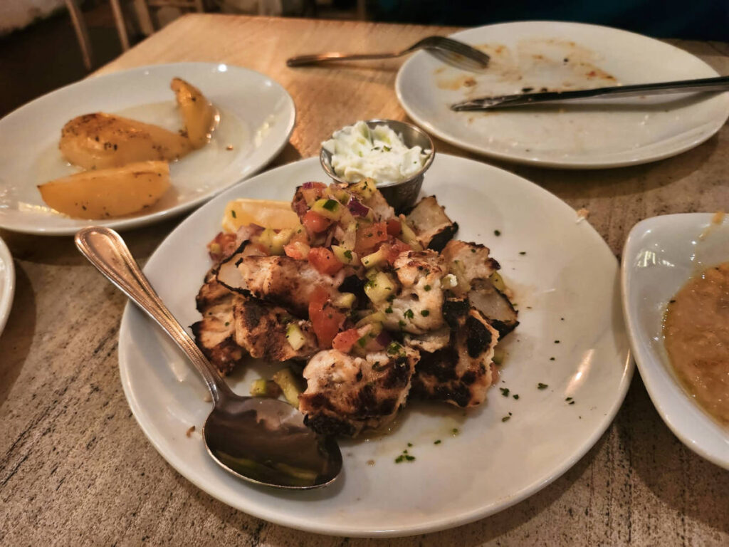 A plate of chicken skewers with a side of tzatziki and lemon potatoes from Aliada