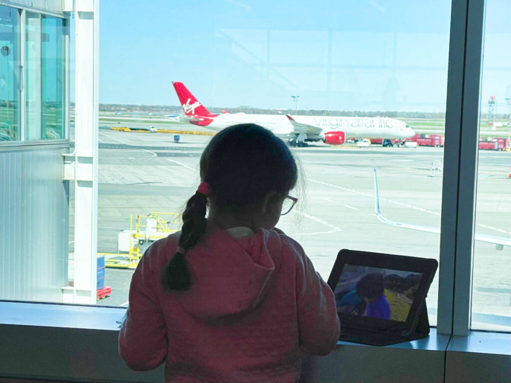 A child watching a movie on her tablet with an overlooking view of the planes on the taxiway