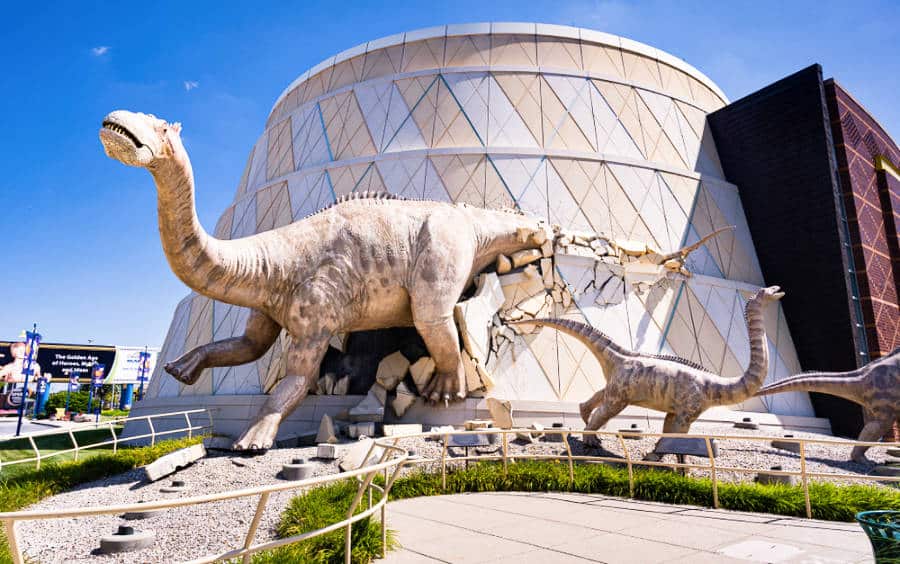 A huge dinosaur and small dinosaur statues at the entrance of the Children's Museum of Indianapolis