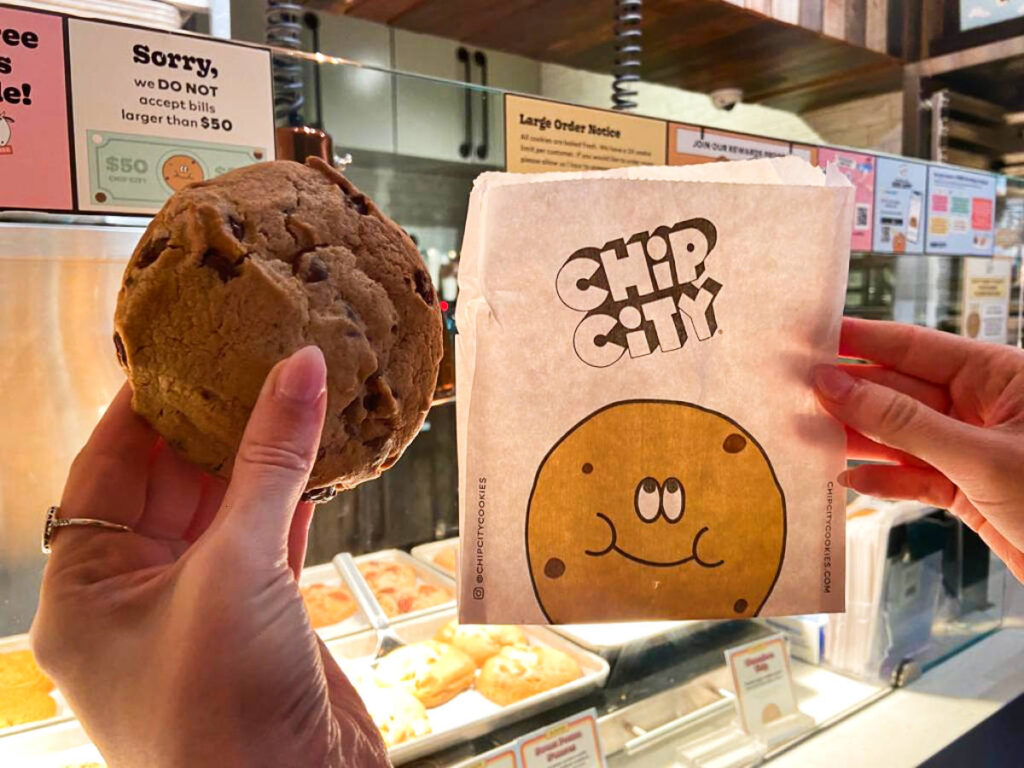 A hand holding a chocolate chip cookie from Chip City