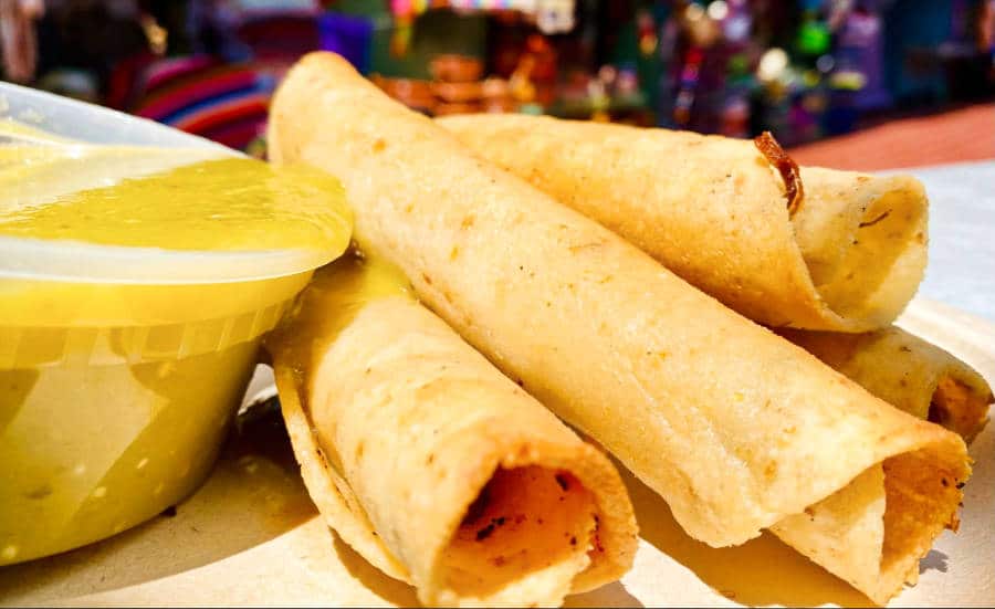 Four pieces of taquitos and a sauce on a plate
