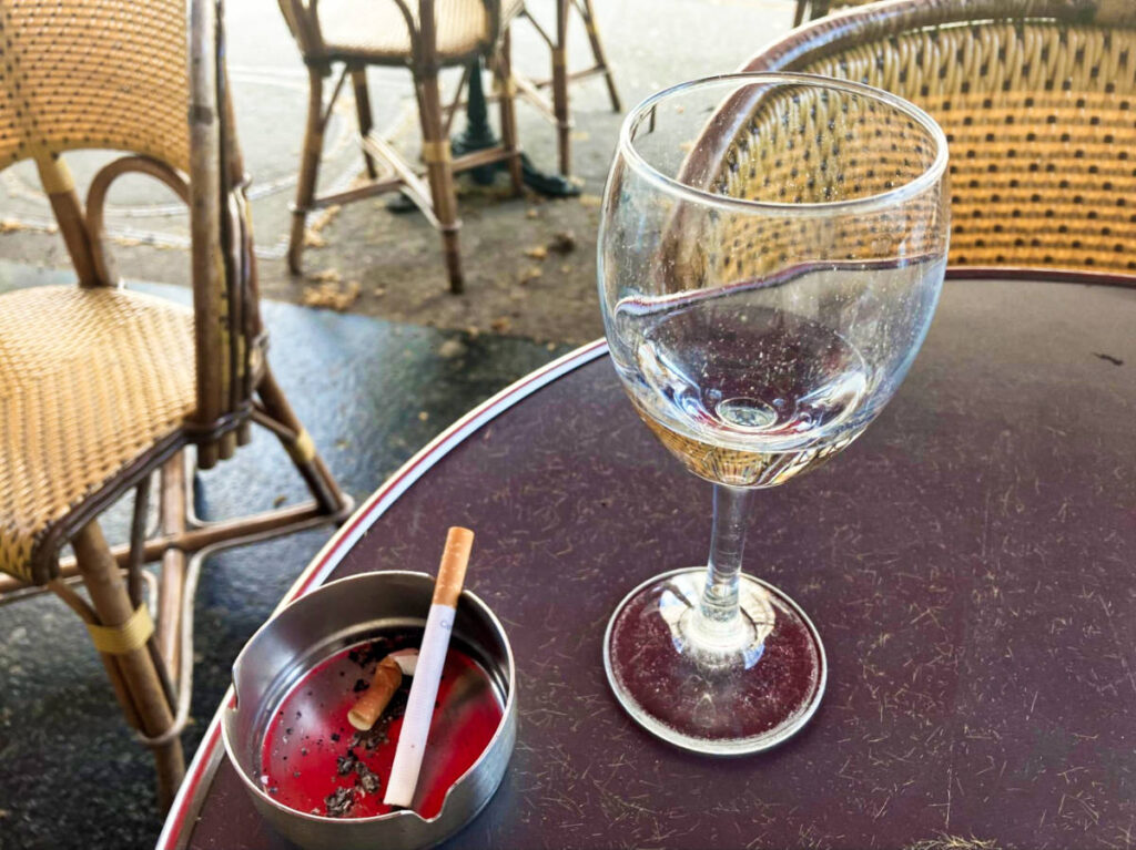 A glass of water and a cigarette on the ash tray at a French café