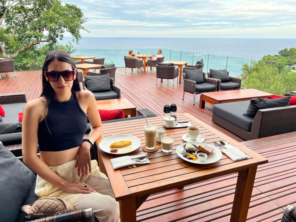 The author's partner, Clara, sitting at the outdoor tables with her breakfast at Paresa Resort